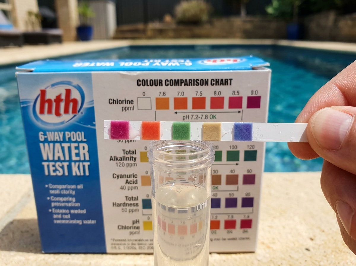 pH test strip color chart next to pool water sample showing acidic, neutral, and basic zones