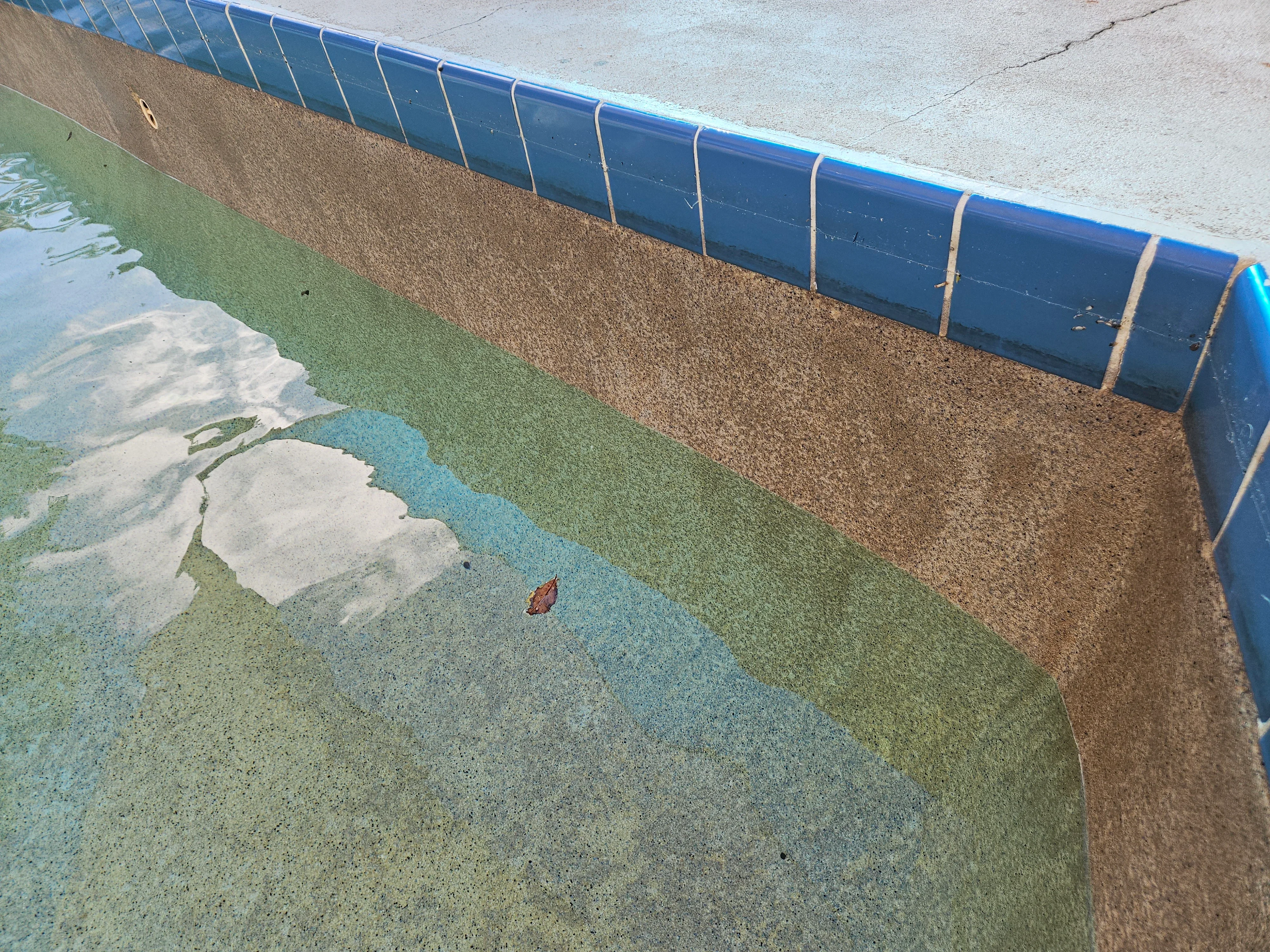 Colored concrete pool deck with blue and green paving, gravel border, and vinyl pool liner installation