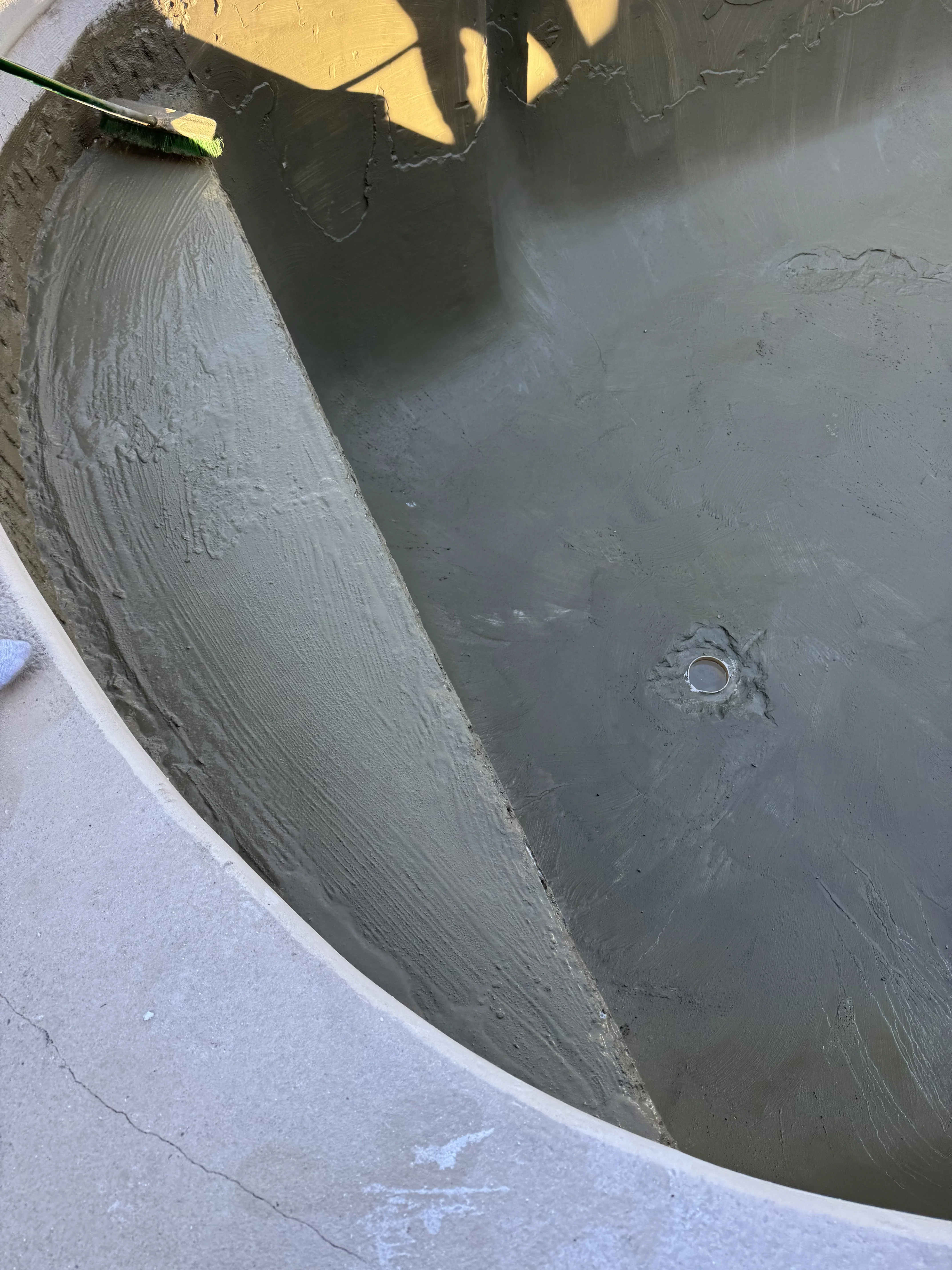 Freshly troweled concrete pool deck with drainage fixture and smooth finish