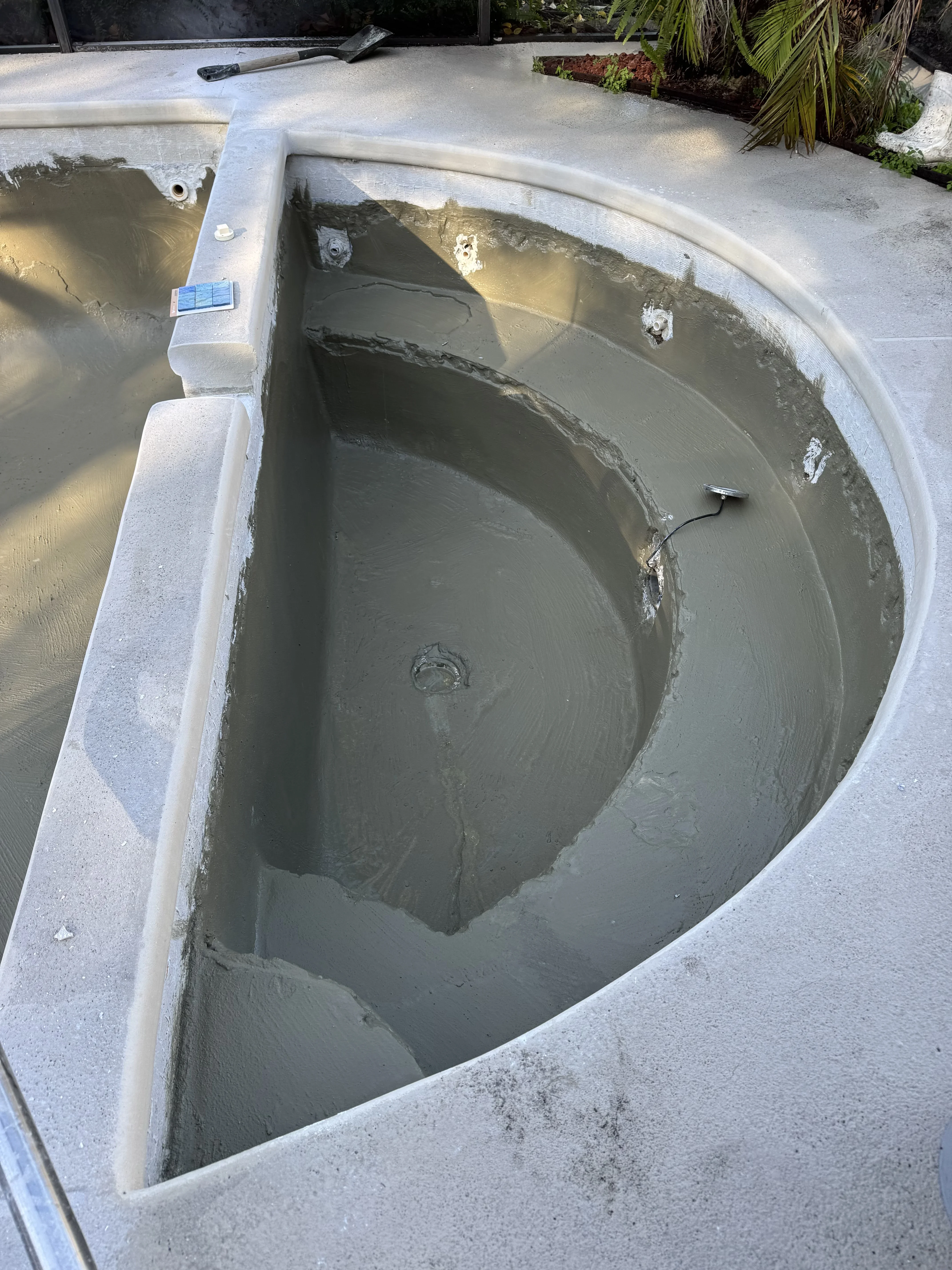 Fiberglass pool interior with fresh gray plaster coating and white coping edge